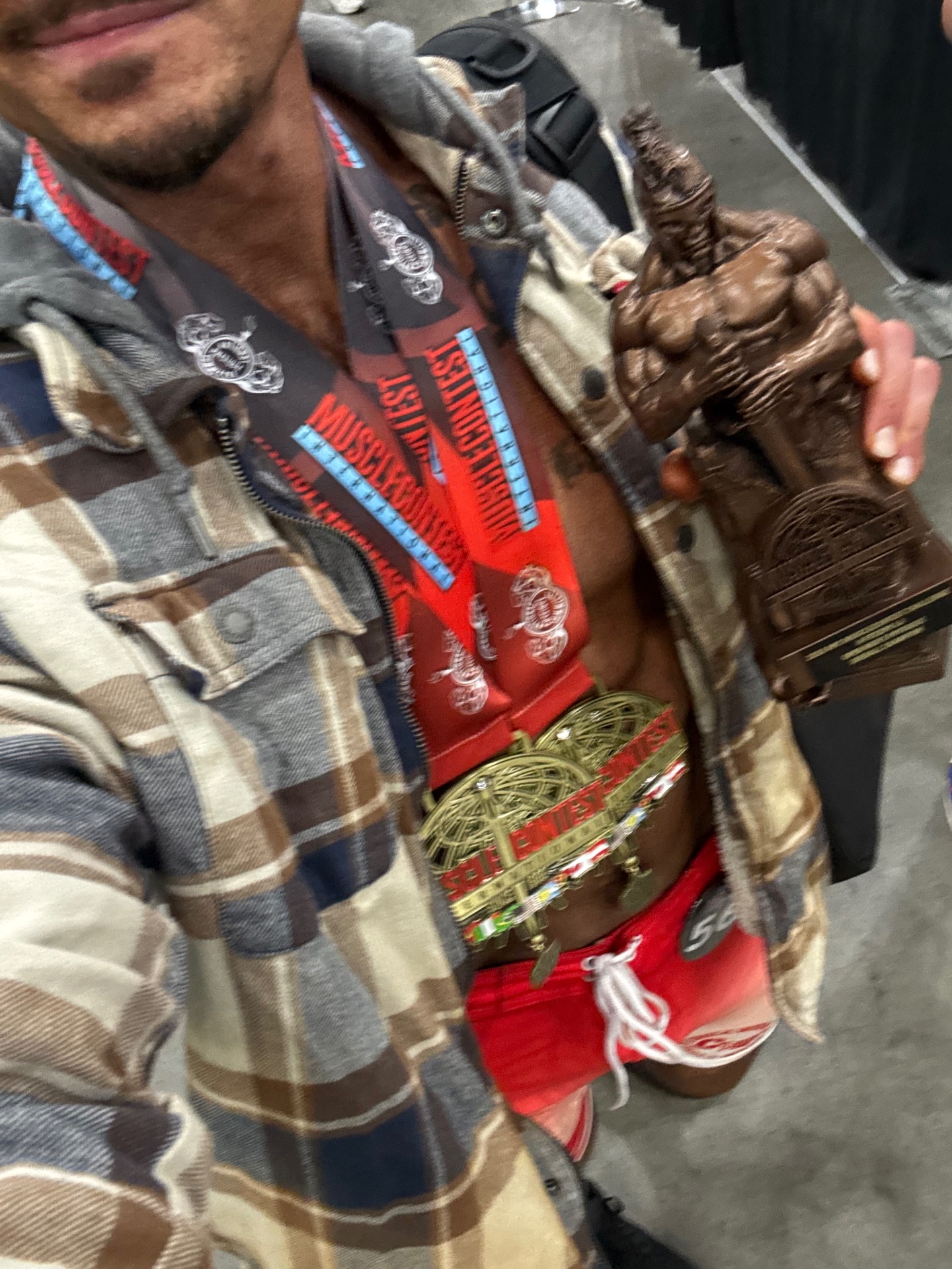 Nick Antap holding his bodybuilding trophy and competition medals